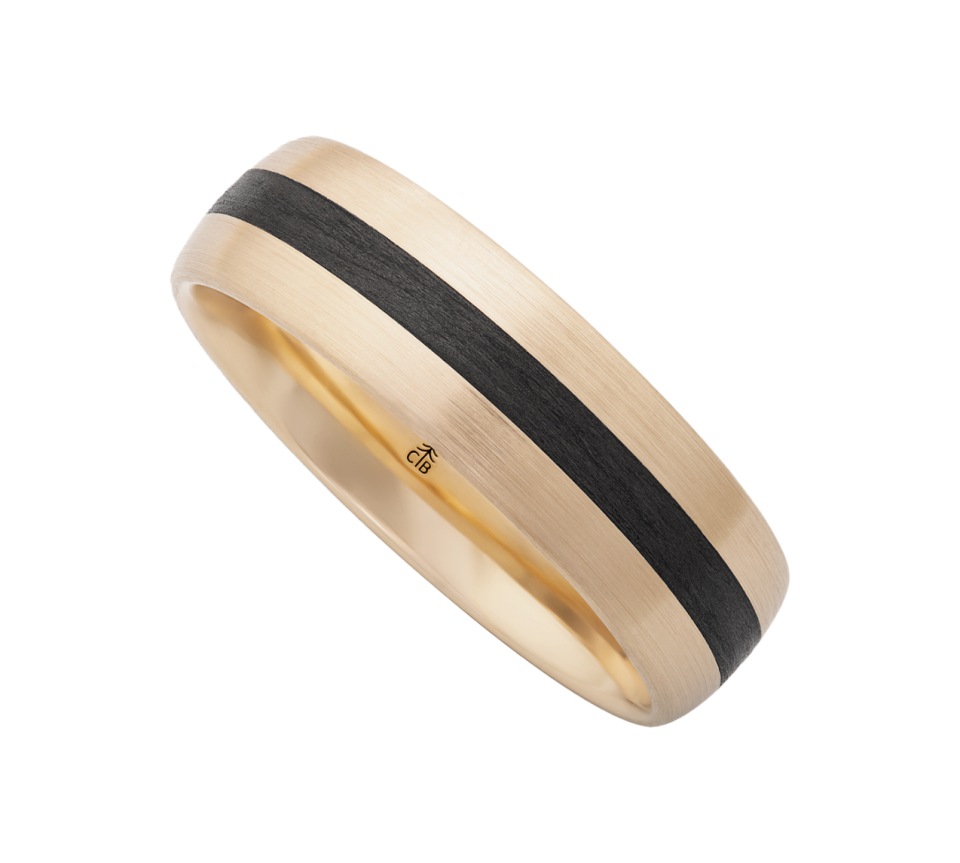 Gold-toned band with a central black satin stripe, a two-tone wedding-style ring viewed at an angle